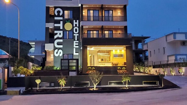 Ein modernes Hotel mit einem auffälligen 'CITRUS'-Schild, das einen zweistöckigen Bau mit einem Balkon im oberen Stockwerk zeigt.