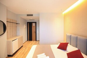 A modern hotel room with a bed, a bedside table, a mirror, and a door leading to another room. - Hotel Citrus (Ksamil)