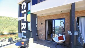 Ein moderner Hotelbalkon mit Hängesessel, Tisch und Blick auf die umliegende Landschaft.