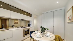 A modern kitchen with white cabinetry, a central island, and a dining area with a round table set for four.