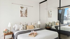 Ein modernes Hotelzimmer mit einem großen Bett, zwei Nachttischen, einem Spiegel und Bildern an den Wänden.