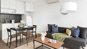 Eine moderne Küche mit weißen Schränken, einer schwarzen Spritzschutzwand und einem Essbereich mit Tisch und Stühlen.
