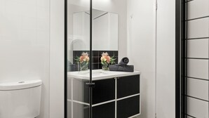 Ein modernes Badezimmer mit Toilette, Waschbecken und Spiegel.