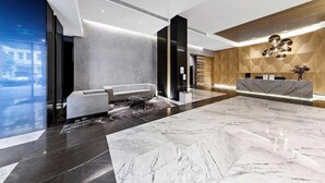 Un vestíbul modern amb taulell de recepció, zona d'estar i ampli paviment de marbre.