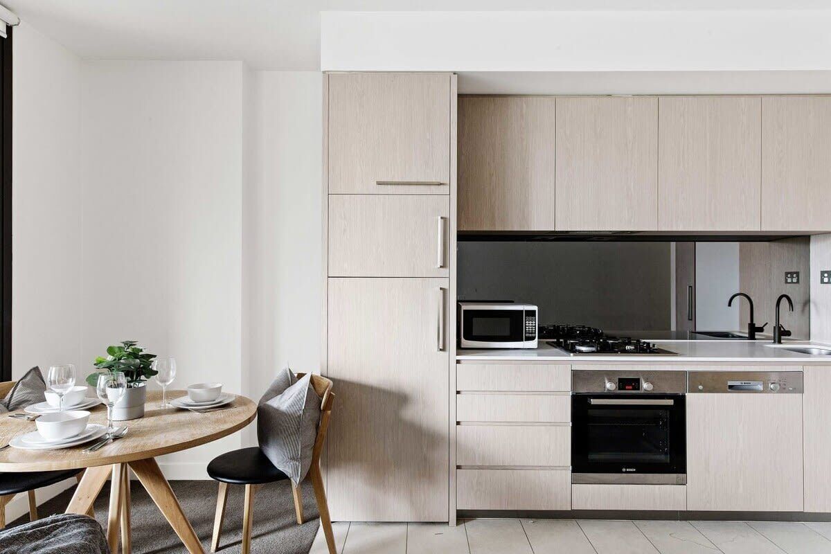 A modern kitchen with light wood cabinets, a built-in microwave, stove, and dishwasher.