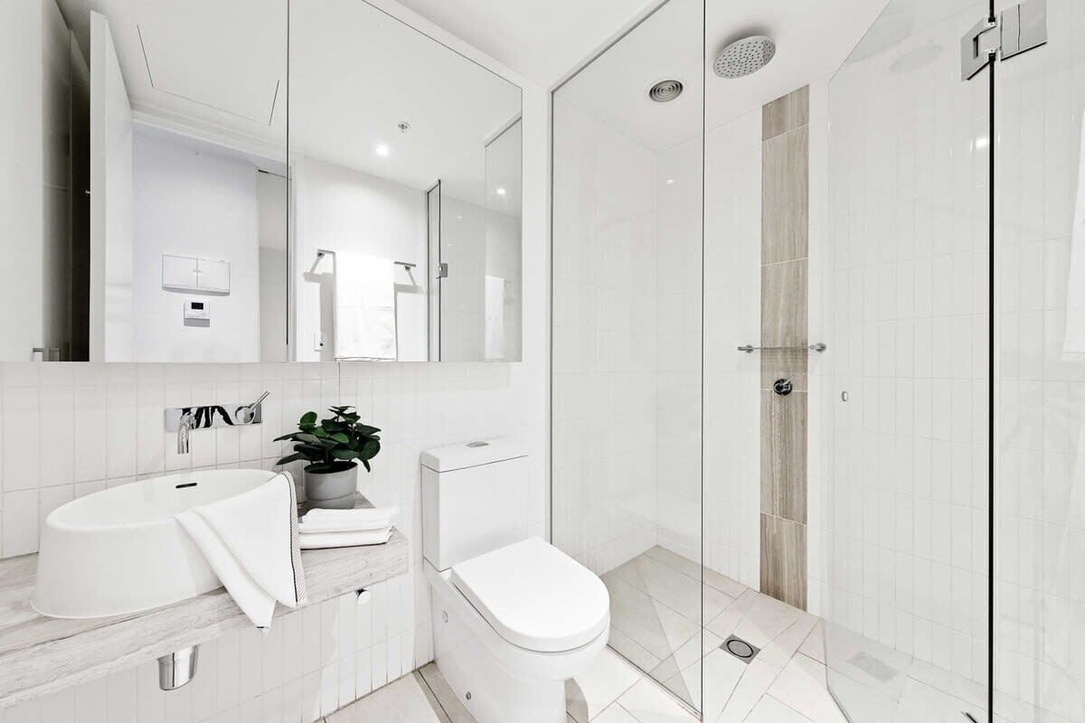 Ein modernes Badezimmer mit Duschkabine aus Glas, einem weißen Waschbecken und einer Toilette.