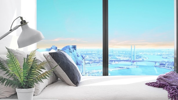 Een moderne slaapkamer met een groot raam dat uitkijkt over een stadsgezicht, inclusief een brug en wolkenkrabbers.