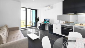 A modern kitchen with a dining area, a sofa, and a large window. - Stylish CBD Apartment With Stunning Harbour Views (Melbourne)