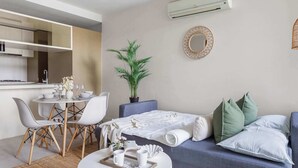 Une chambre d’hôtel moderne comprenant un coin repas, un lit avec des oreillers, une plante en pot et un miroir fixé au mur.