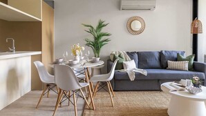 Un espace de vie moderne comprenant une table à manger, des chaises, un canapé, une plante en pot et un luminaire suspendu.