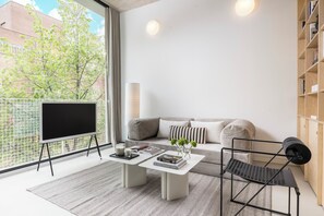 A modern living room with a flat-screen TV, a coffee table, a sofa, and a bookshelf.