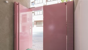 A pink door leading to an outdoor area with a tiled floor and a building in the background. - Edmond Vibes Avenida de América (Madrid)