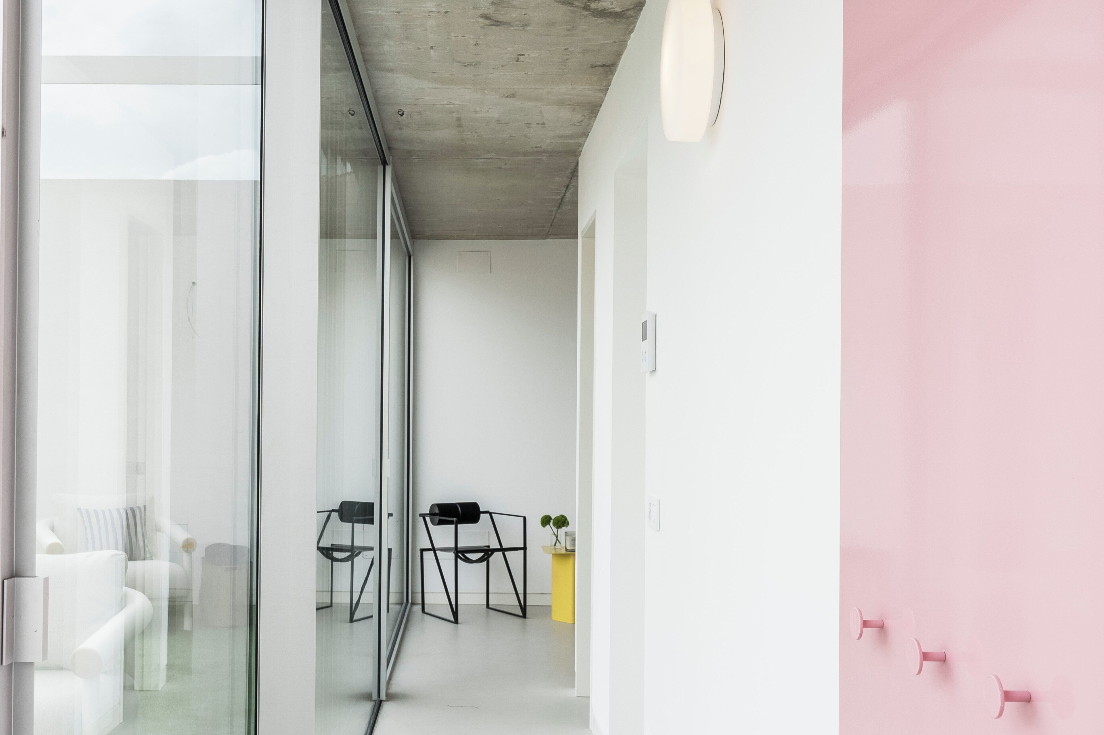 A modern interior with glass walls, a concrete ceiling, and a pink wall.
