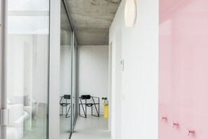 A modern interior with glass walls, a concrete ceiling, and a pink wall.