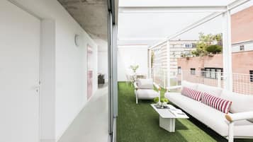 Un apartamento moderno con interior blanco, piso de césped artificial verde, sofá blanco con almohadones a rayas y una mesa de centro blanca.