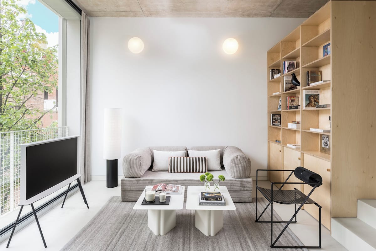 A modern living room with a sofa, two coffee tables, a TV, and a bookshelf.