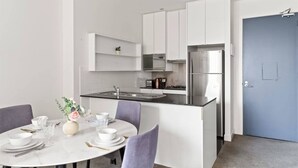 A modern kitchen with white cabinets, a stainless steel refrigerator, and a blue door. - A Cozy 2BR Apt on Collins Near Flinders Station (Melbourne)