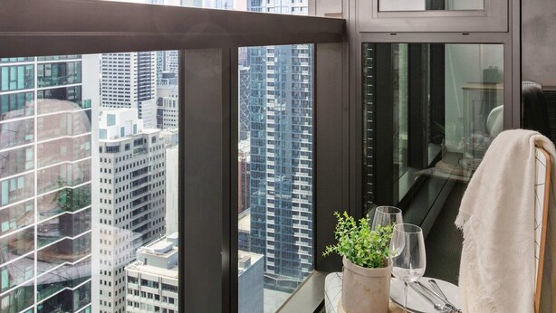 A balcony with a city view, a small table with a plant, a wine glass, and a towel. - Pet-friendly 2BR Near Southern Cross, City Views (Melbourne)
