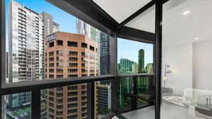 A modern apartment with large floor-to-ceiling windows offering views of surrounding high-rise buildings and a cityscape. - A Cozy Apt, Only a 5-min Walk to Victoria Market (Melbourne)