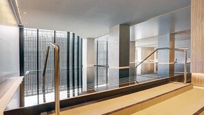 A modern indoor area with a glass railing, a staircase, and a wall with a geometric pattern. - A Cozy Apt, Only a 5-min Walk to Victoria Market (Melbourne)
