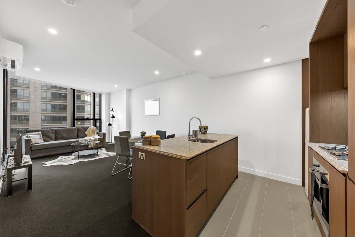 A modern apartment with a kitchen island, a sofa, and a dining area.