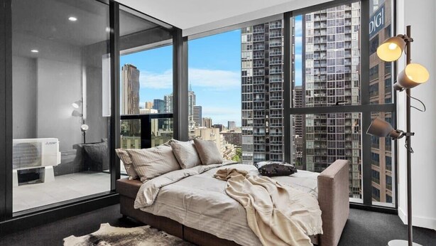 A modern bedroom with a large window, a bed, a floor lamp, and a heater. - A Cozy Apt, Only a 5-min Walk to Victoria Market (Melbourne)