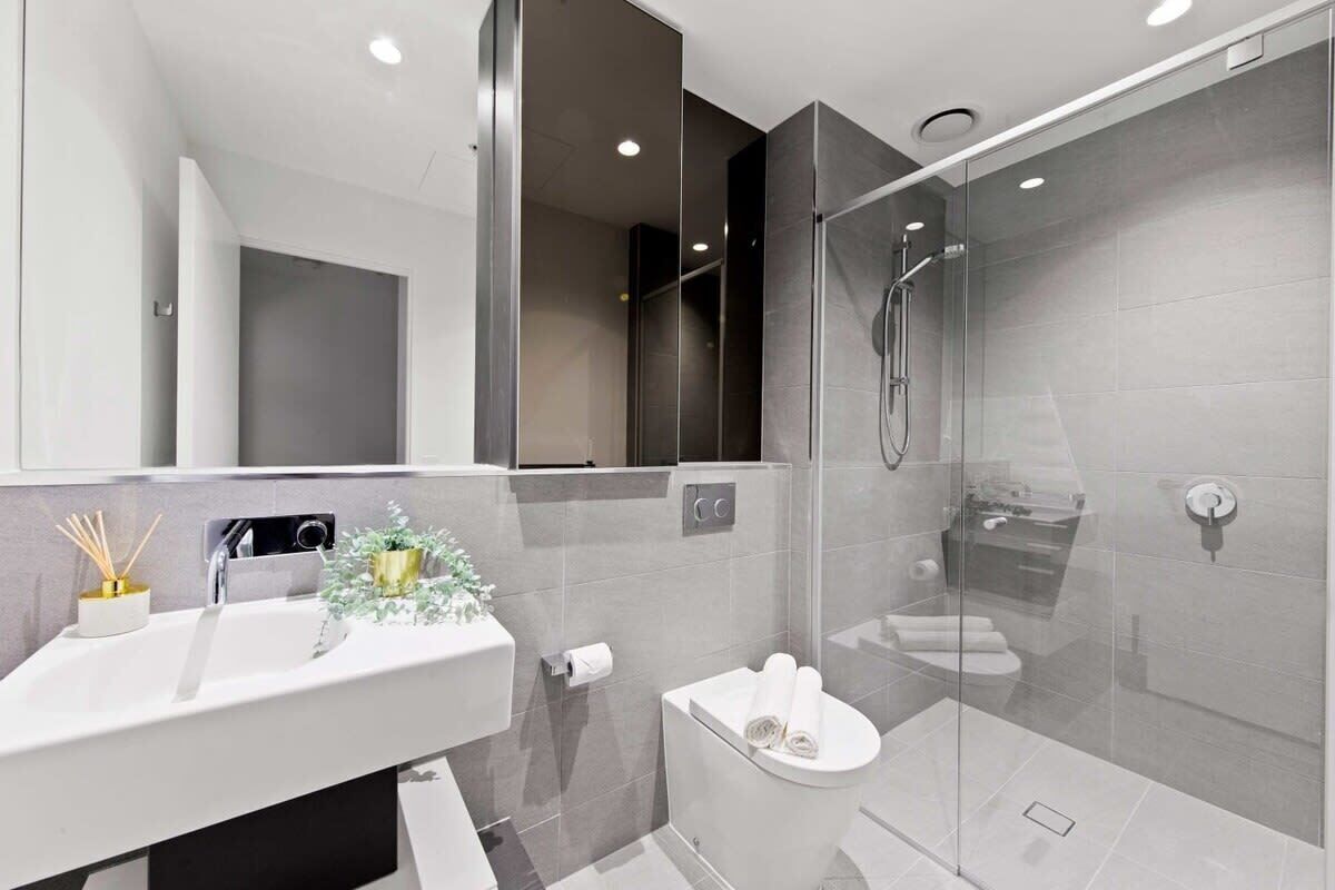 A modern bathroom with a glass shower enclosure, a white sink, and a toilet.