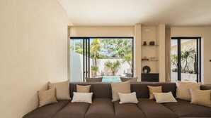 A modern living room with a large sectional sofa, a pool view, and a minimalist decor. - Pala House by Alfred in Bali (Pecatu)