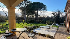 Eine Außenpatio-Terrasse mit einer Pergola, Sitzgelegenheiten und Blick auf den Garten.