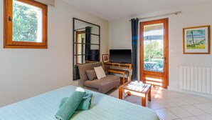 Ein Zimmer mit einem Bett, einem Sofa, einem Fernseher, einem Tisch und einem Fenster.