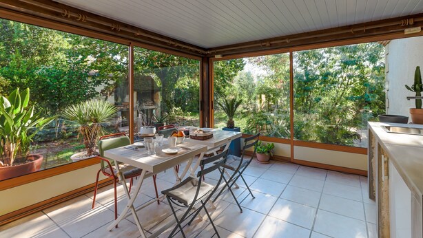 Eine sonnendurchflutete Terrasse mit Tisch, Stühlen und Kübelpflanzen.