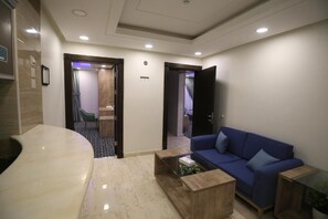Una hall d'albergo moderna con una reception a forma di curva, un divano blu e un tavolino da caffè.