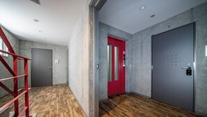 A modern interior with a red door, grey walls, and wooden flooring. - ANAX NORD 403 (Sapporo)