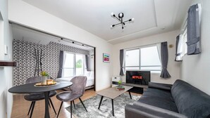 A modern living room with a sofa, a dining table with chairs, a TV, and a large window with curtains. - ANAX NORD 403 (Sapporo)