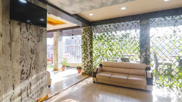 Un intérieur moderne avec un canapé beige, un mur à texture et un paravent végétal vert.
