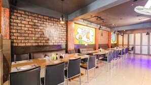Un restaurant aux murs de briques, aux longues tables et aux chaises noires.