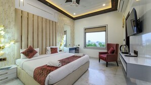 A modern hotel room with a large bed, a desk, a chair, and a television. - Prince Diamond Hotel (Varanasi)