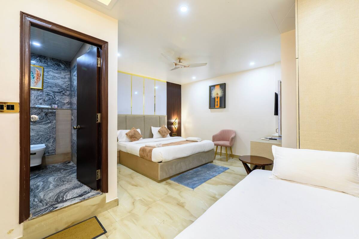 A modern hotel room with a large bed, a separate bathroom with a marble wall, a ceiling fan, and a flat-screen TV.
