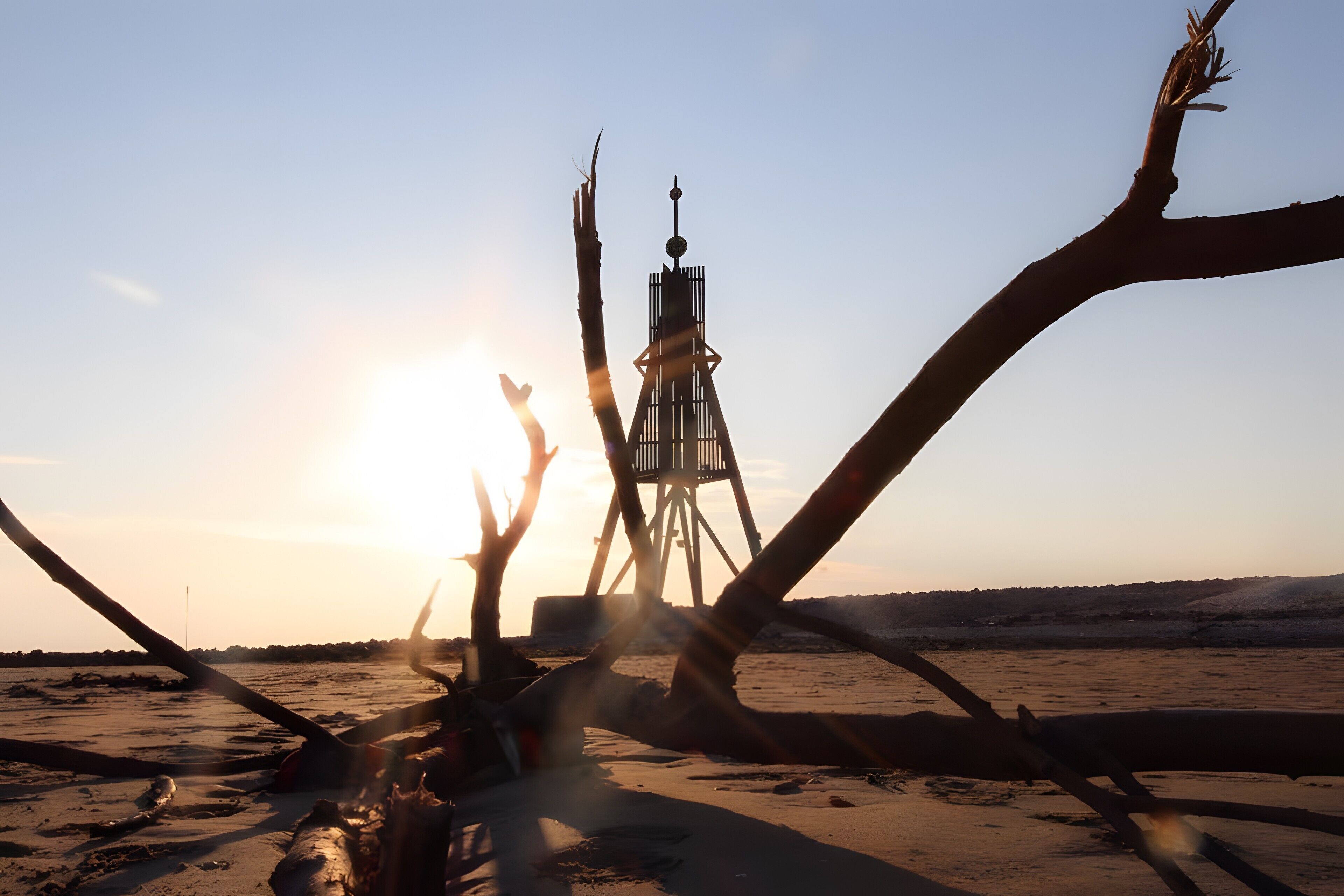 A desert landscape with a tall, narrow tower structure in the center.