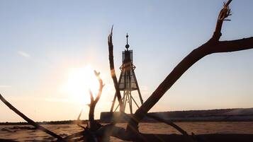 A desert landscape with a tall, narrow tower structure in the center.