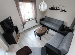 Een woonkamer met een bank, een salontafel, een televisie en een wanddecoratie.