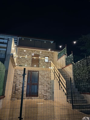 A two-story building with a balcony, a staircase, and a gated entrance.