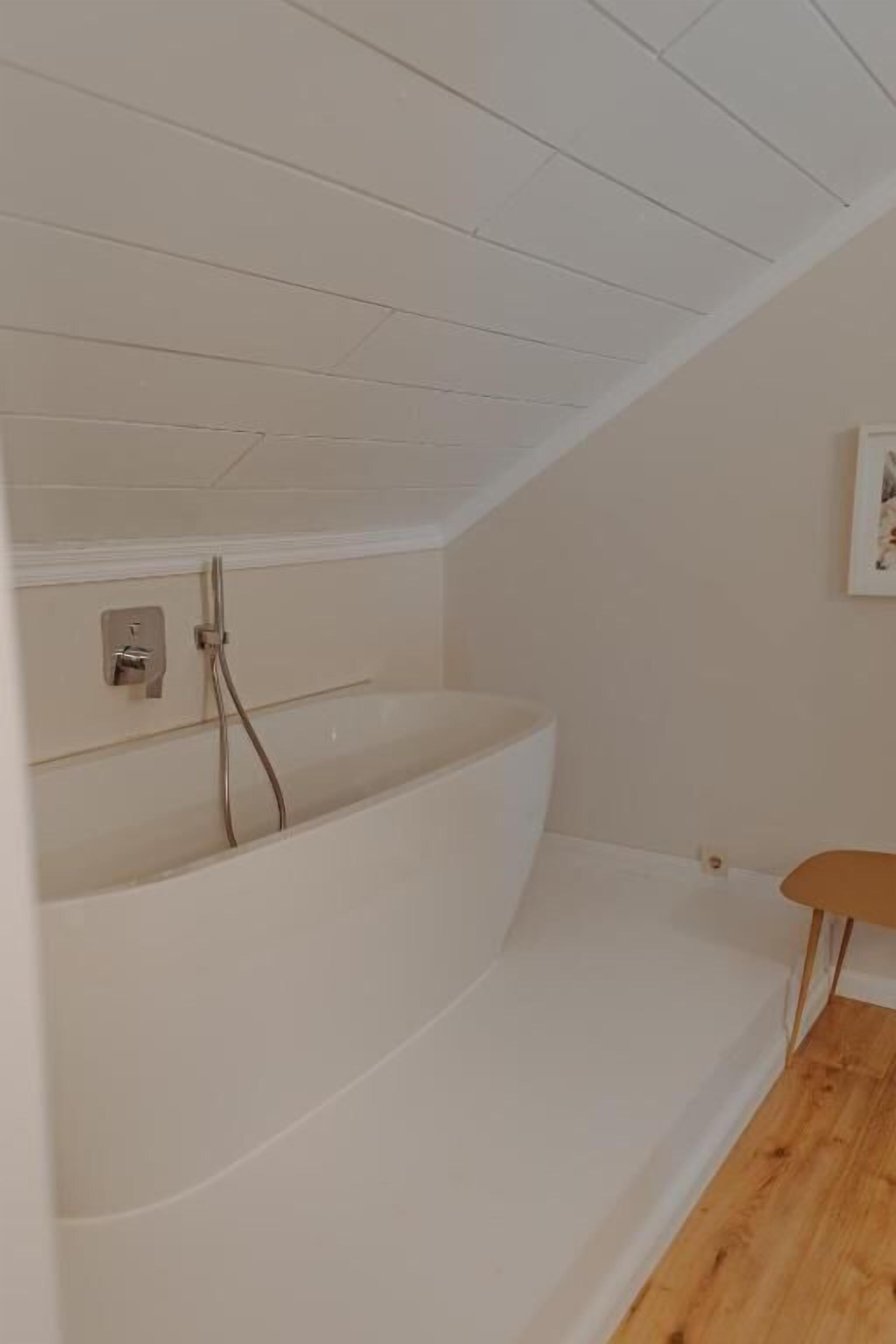 Ein modernes Badezimmer mit einer integrierten Badewanne, Holzboden und einem kleinen Tisch.