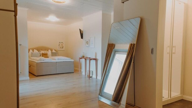 A hotel room with a bed, a bedside table, and a mirror leaning against the wall. - Haggn&Co (Neukirchen)
