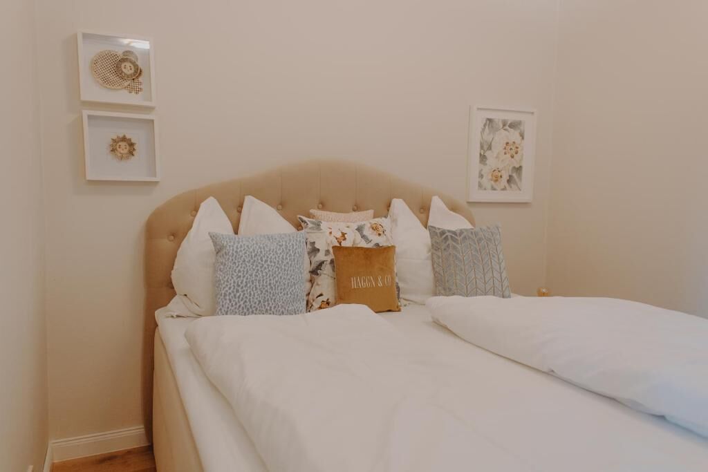 Una cama bien tendida con varios almohadones y un cabecero.