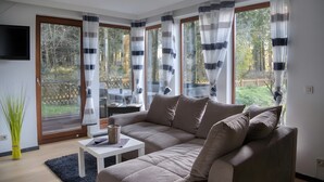 A modern living room with a sectional sofa, a small table, and a TV mounted on the wall.