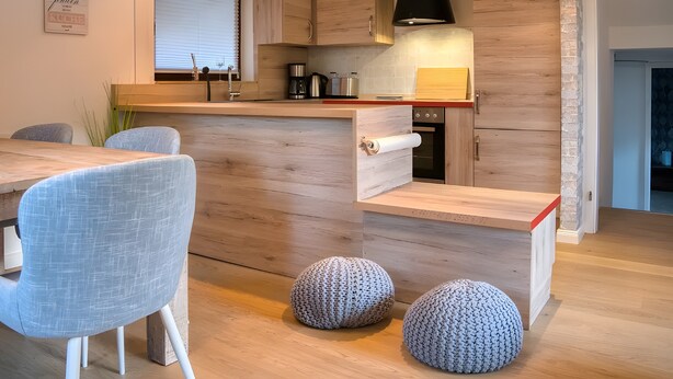 A modern kitchen with wooden cabinetry, a built-in microwave, and a red countertop.