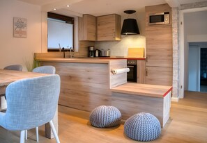 A modern kitchen with wooden cabinetry, a built-in microwave, and a red countertop.