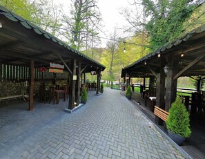 A covered outdoor seating area with stone walls, wooden benches, and potted plants.