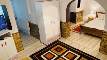 A hotel room with a bed, a wardrobe, a television, and a patterned rug.
